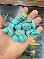Hand holding blue-green rough stone nuggets
