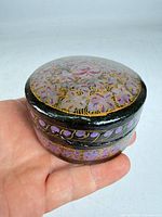 Top and side view of round Indian lacquer box showing floral painting and lid fit