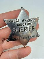 Front view of silver-tone six-point star badge reading Palm Springs Honorary Sheriff Desert Circus