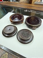 Four wooden vase stands, two large carved and two small flat