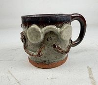 Front view of handmade mug showing spectacles and moustache relief, glaze colours visible