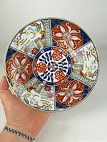 full view of hand holding front of Imari plate showing complete design