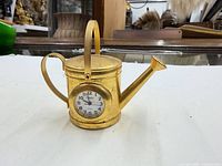 Front view of gold-tone Timex watering can desk clock showing dial