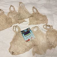 Seven cotton mesh bags and packaged Baggler holder laid out on floor