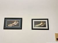 Both framed prints hanging side by side on wall