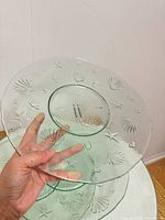 Top view of one dish showing shell and starfish relief, hand holding to indicate scale and transparency