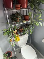 Full view of metal rack positioned over toilet, showing three shelves and arched top