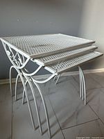 Three white iron nesting tables stacked