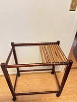 Full view of wooden pant valet stand showing frame and casters