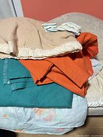 Pile of assorted blankets and comforter on sofa