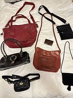 Group shot of seven bags and wallet laid out on white background