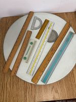 Group view of six rulers and one protractor on round surface