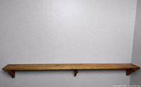Full view of long wooden shelf mounted on wall