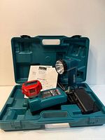 Open teal case displaying flashlight, charger, battery, adapter and manual