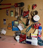 Overall pegboard with tools, brushes, tape and hardware visible