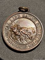 Obverse of medal showing society name, rescue scene