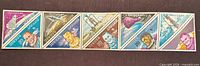 Full horizontal strip showing seven attached triangular astronaut stamps
