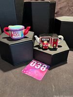 Both miniature teapots front view on display blocks