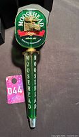 Full view of Moosehead Lager tap handle beside lot tag