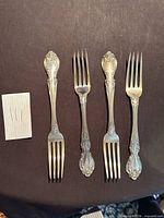 Four ornate silver dinner forks with decorative handles