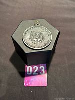 Medal on stand showing obverse text and crest