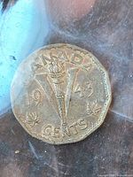 Reverse side of 1943 Canada V nickel in flip showing torch design and date