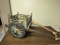 Left side view of cast iron wagon showing wheels, tongue and bed