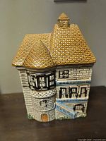 Front view of ceramic house cookie jar with turret and roof lid attached