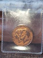 Obverse of coin showing twin busts and dates in plastic sleeve