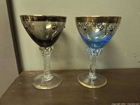 Pair of blown glass goblets, different bowl colors, decorative stems, gold overlay and jewels