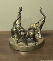 Front view of brass three-elephant sculpture