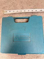 Closed teal Alltrade case with ruler for scale