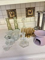 overview of assorted glass, metal and ceramic candleware on countertop