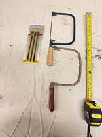 Lot overview showing two coping saws, sealed blade pack, tape for scale