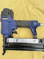 Full right-side view of Campbell Hausfeld pneumatic brad nailer / stapler on yellow background