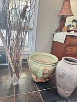 Group view showing ceramic planter on stand, tall ceramic vase, glass vase with branches