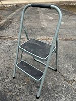 Full view of two-step folding ladder showing frame, steps, handle and feet