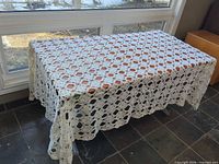 Full view of crochet lace tablecloth on rectangular table, demonstrates size and overall pattern