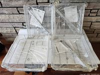 Four wire baskets wrapped in plastic with instruction sheets and rails visible