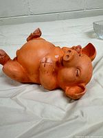 Side view of pig figurine lying on back, showing overall appearance and finish