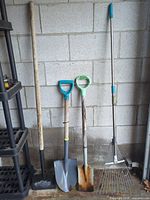 All four yard tools leaning against wall