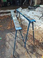 Two blue folding sawhorses open on driveway