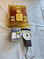 Overview showing Travel Smart converter kit blister pack, Travel Smart All-in-One adapter box, and Air Canada luggage scale