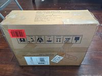 Sealed shipping carton front with SKU and handling icons visible