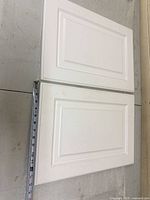Front view of both white raised-panel cabinet doors