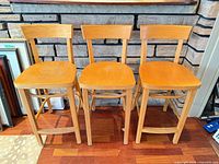 Front view of the three wooden counter-height stools showing overall design and finish