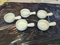 Top view of five matching white ceramic handled dishes