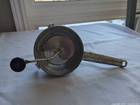 Top view showing perforated base, crank mechanism, handle