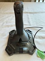 Top view of Logitech Attack 3 joystick showing handle, buttons, base logos, and attached USB cable