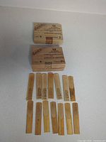 Two vintage Rico wooden reed boxes marked strength 2 and 2½ with twelve loose reeds displayed